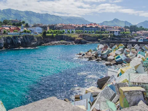 Cubos de la Memoria coloridos en el puerto de Llanes con montañas al fondo