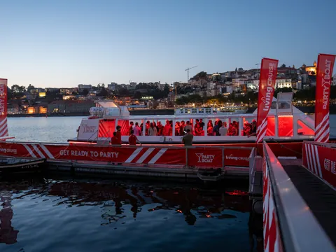 Barco de fiesta iluminado al anochecer frente a la ciudad de Oporto.