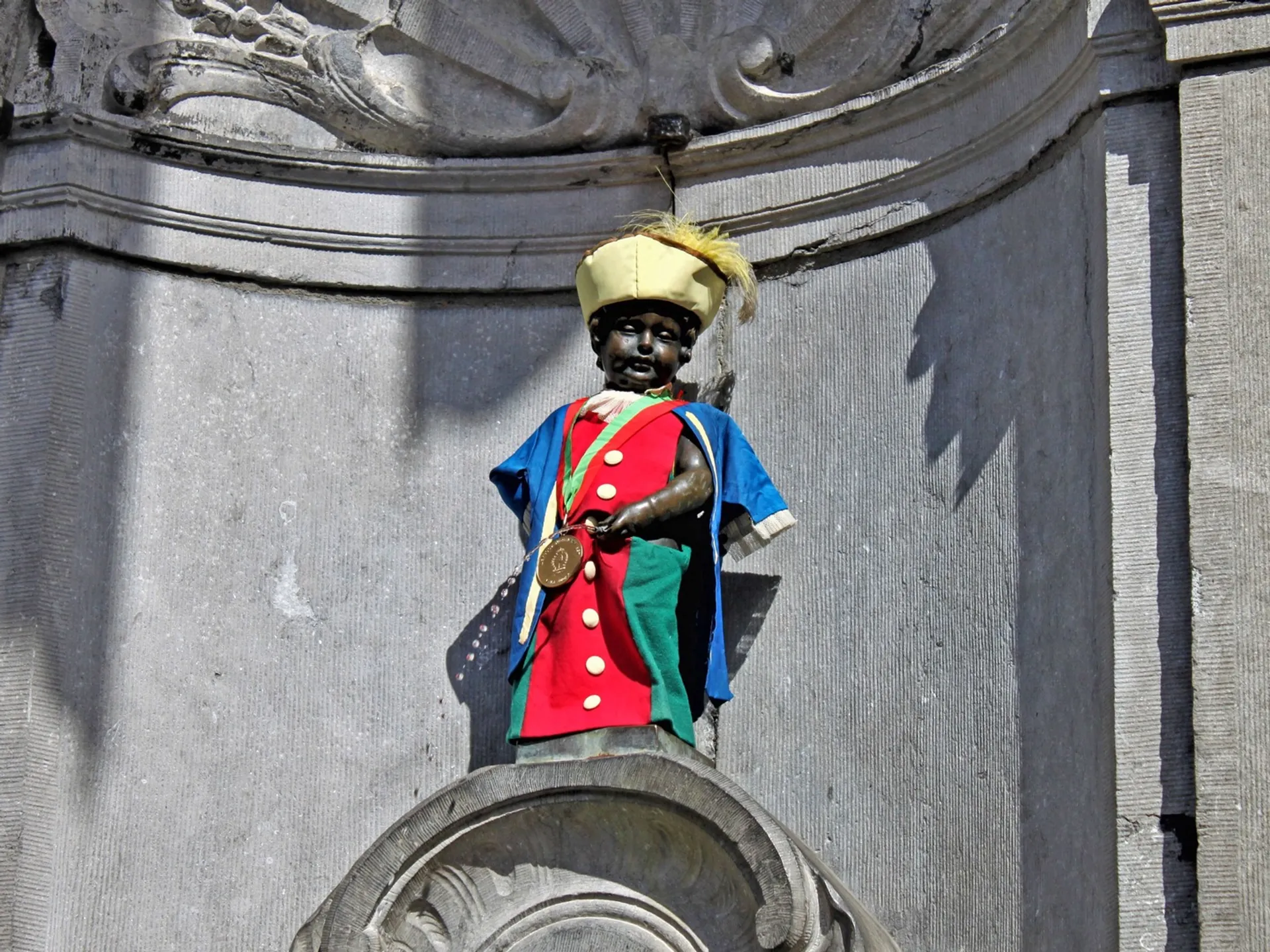 Estatua del Manneken Pis vestido con traje regional en su fuente de Bruselas.