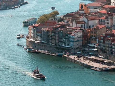 Vista de la ribera de Oporto con casas coloridas y barcos navegando por el río Duero.