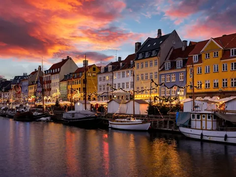 Atardecer navideño en Nyhavn, con las fachadas de colores iluminadas y el canal reflejando el ambiente mágico de Copenhague.