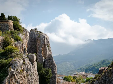 Vista del castillo de Guadalest sobre rocas y montañas, con el valle y el pueblo al fondo.