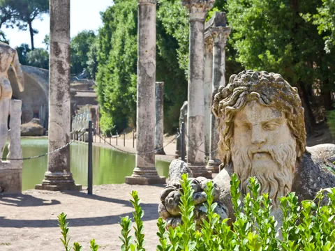 Estatuas y columnas romanas junto a estanque rodeado de vegetación en Villa Adriana, Tívoli.