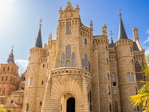 Palacio Episcopal de Astorga, León, diseño modernista de Gaudí, con torres y almenas bajo un cielo azul brillante.