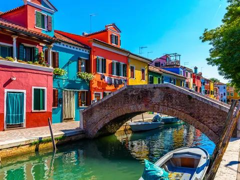 Puente de ladrillo y casas de colores junto al canal de Burano, Venecia