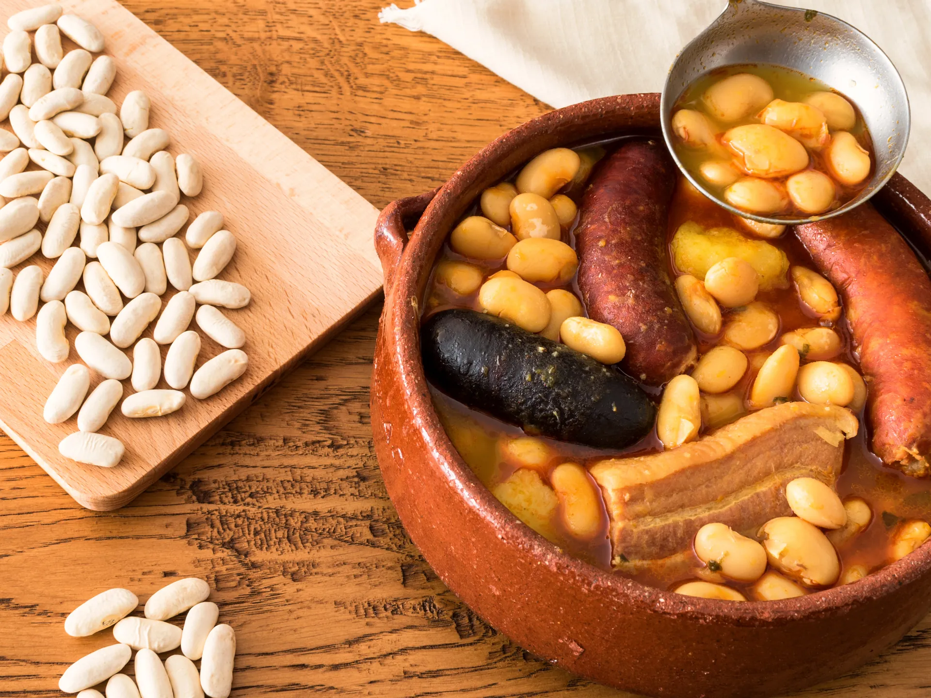 Fuente de Fabada con compango y fabes sin hacer a su lado, plato típico asturiano