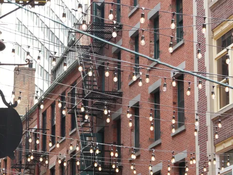 Calle Stone Street en Nueva York con luces colgantes y fachadas de ladrillo estilo histórico.