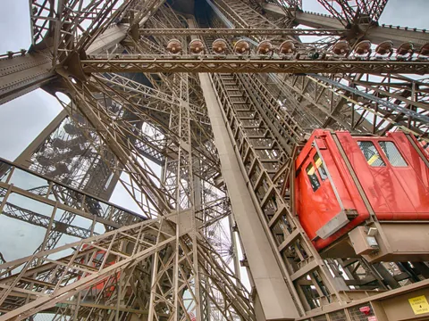 Ascensor rojo subiendo por la estructura de hierro de la Torre Eiffel en París