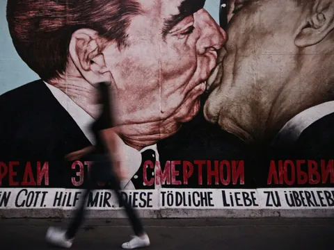 Mural del Beso Fraterno en el Muro de Berlín con persona caminando delante.