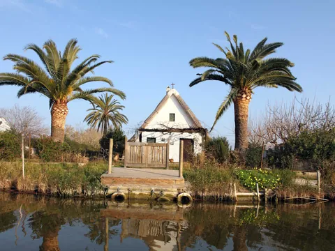 Barraca tradicional reflejada en el agua en la Albufera de Valencia