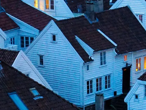 Casas tradicionales de madera blanca y tejados rojizos en Gamle Stavanger, Noruega, al atardecer.