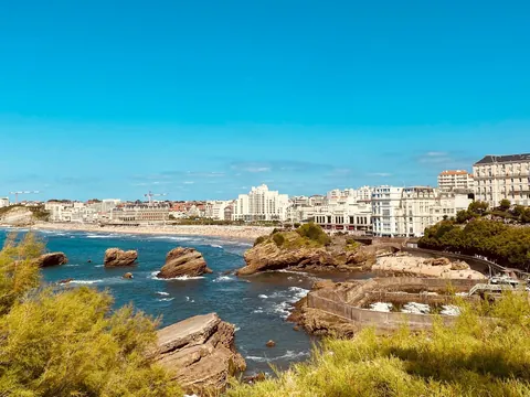 Vista costera de Biarritz con acantilados, playa y edificios junto al mar.