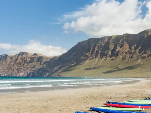 Clase grupal de surf en la playa de Famara