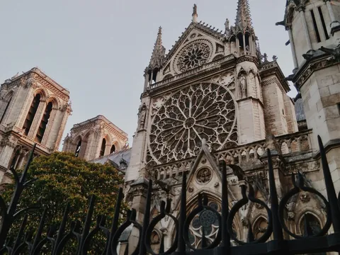 Fachada gótica de la Catedral de Notre Dame en París con rosetón central y torres icónicas vistas desde el exterior.