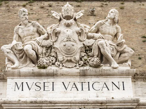 Entrada de los Museos Vaticanos con esculturas y el emblema papal en la Ciudad del Vaticano.