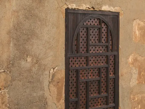 Celosía de madera oscura en muro de la Alhambra, Granada.