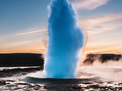 Erupción del géiser Strokkur en el valle de Haukadalur, Islandia, al atardecer entre vapor y aguas termales.