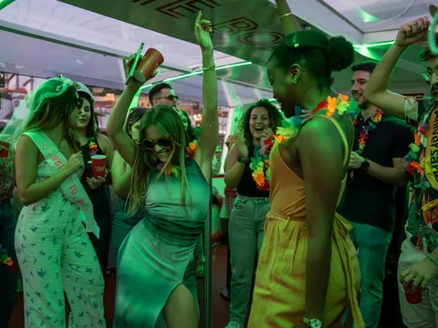 Grupo celebrando y bailando en una fiesta a bordo con luces verdes.