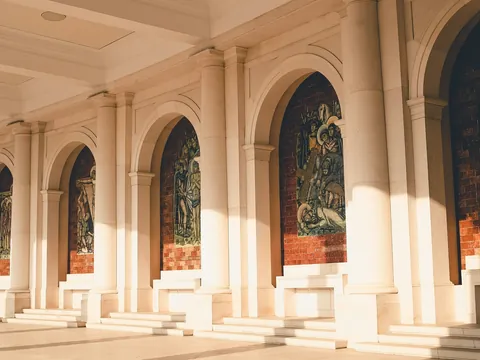Mosaicos religiosos en la columnata del Santuario de Fátima bajo luz cálida.