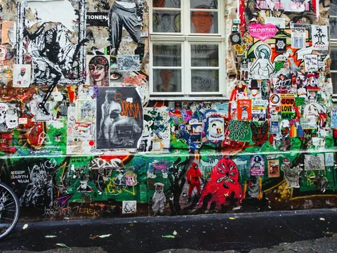 Pared repleta de arte urbano, pegatinas y grafitis coloridos en un callejón alternativo de Berlín