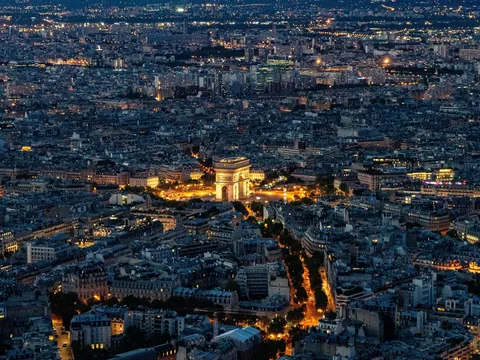 Vista aérea nocturna del Arco del Triunfo iluminado y el horizonte de París.