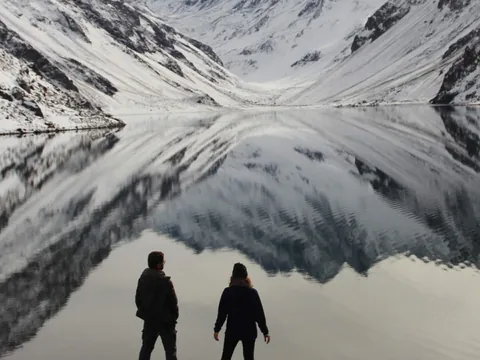 Pareja con las montañas de los Andes reflejadas en la Laguna del Inca en la excursión desde Santiago de Chile.