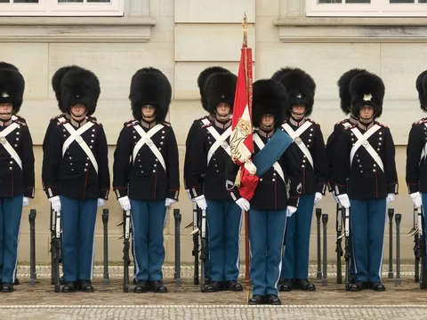 Guardias Reales británicos con uniforme negro y sombreros altos frente a Palacio Buckingham