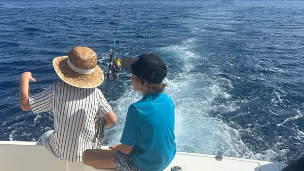 Niños en un barco de pesca en Mallorca, disfrutando del día soleado.