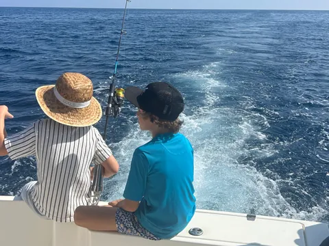 Niños en un barco de pesca en Mallorca, disfrutando del día soleado.